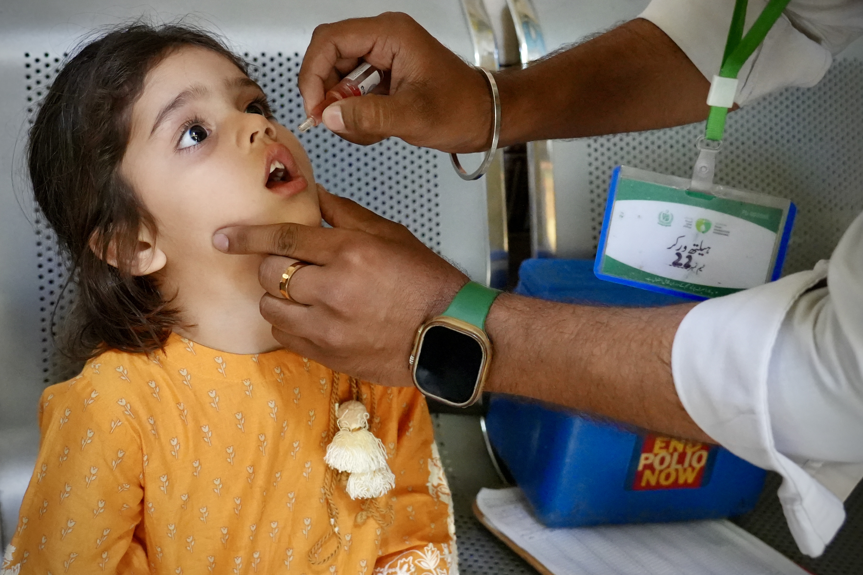 A health worker administering polio drops to a child
